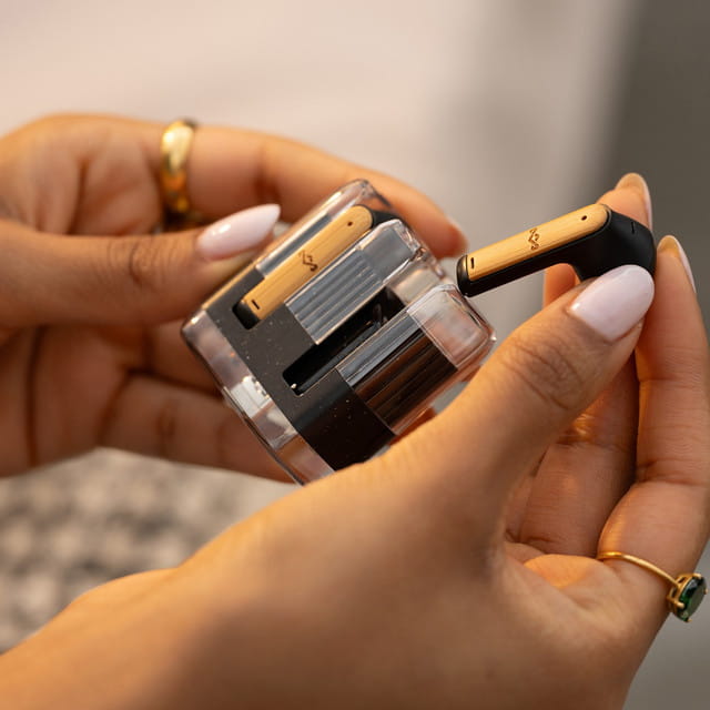 Mujer con paleta de maquillaje y audífonos inalámbricos House of Marley Zion Negros