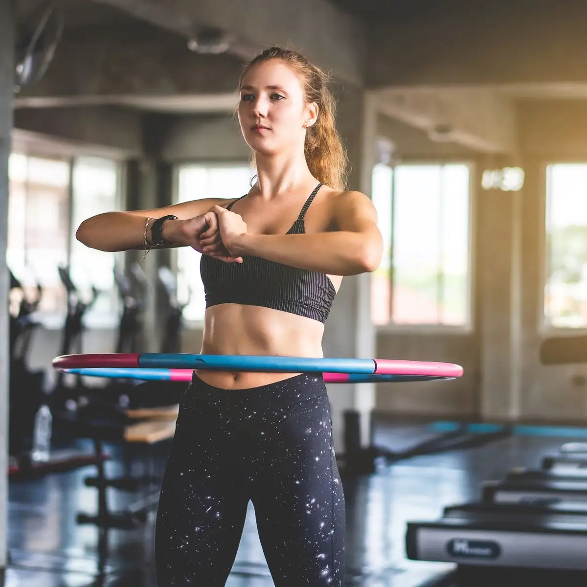 Mujer haciendo hula hoop con Hula Hoop 96 cm Elle Sport SR6349, flexibilidad mientras tonifica.