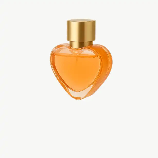 Frasco de perfume de vidrio en forma de corazón con una tapa dorada y líquido naranja.